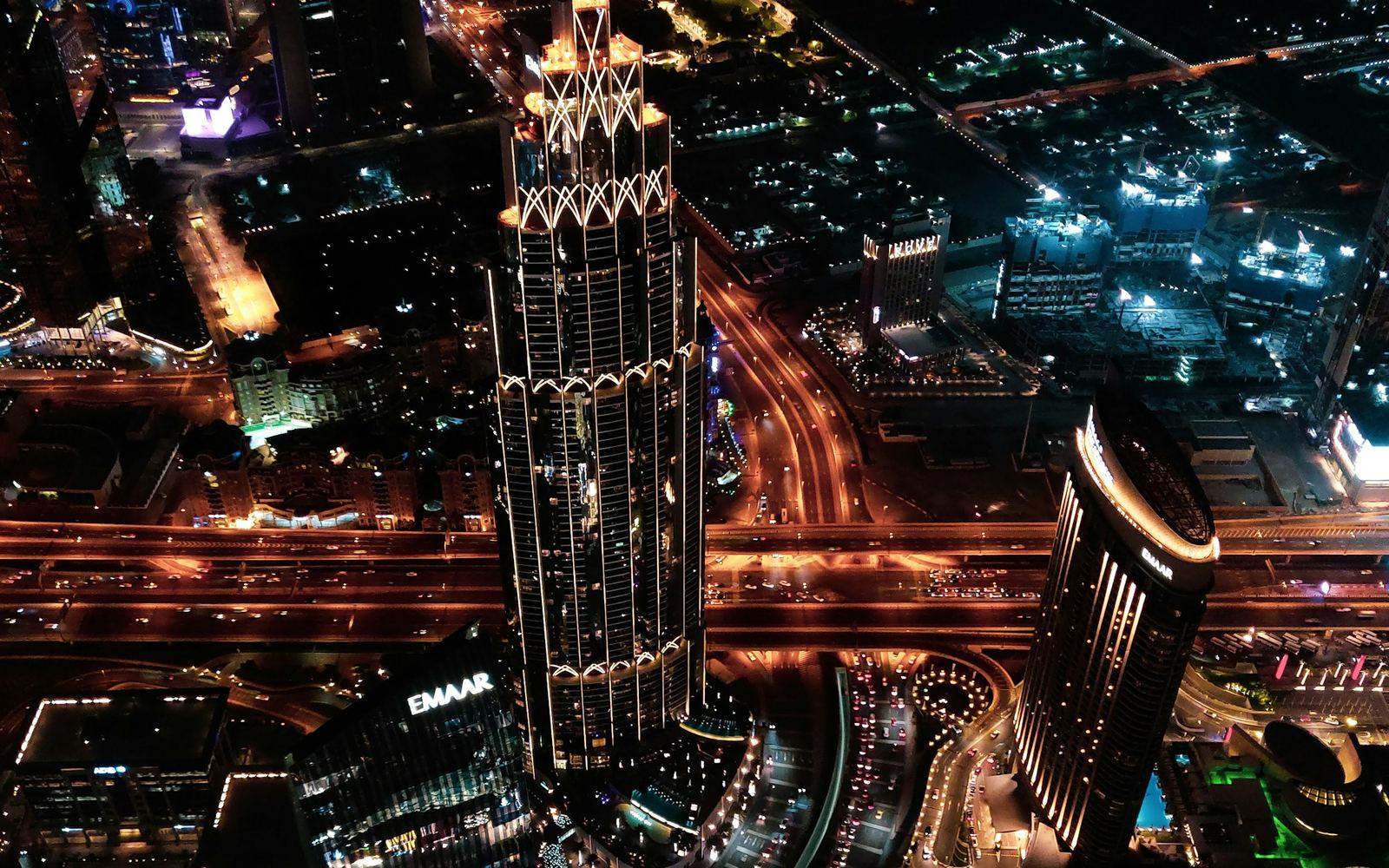 Dubai from the air at night, roads threading between lit towers